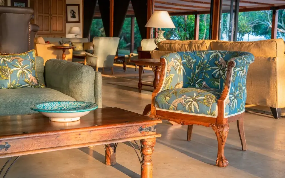 Open lounge with wooden furniture and botanical upholstery, The River Station, Queen Elizabeth NP, Uganda