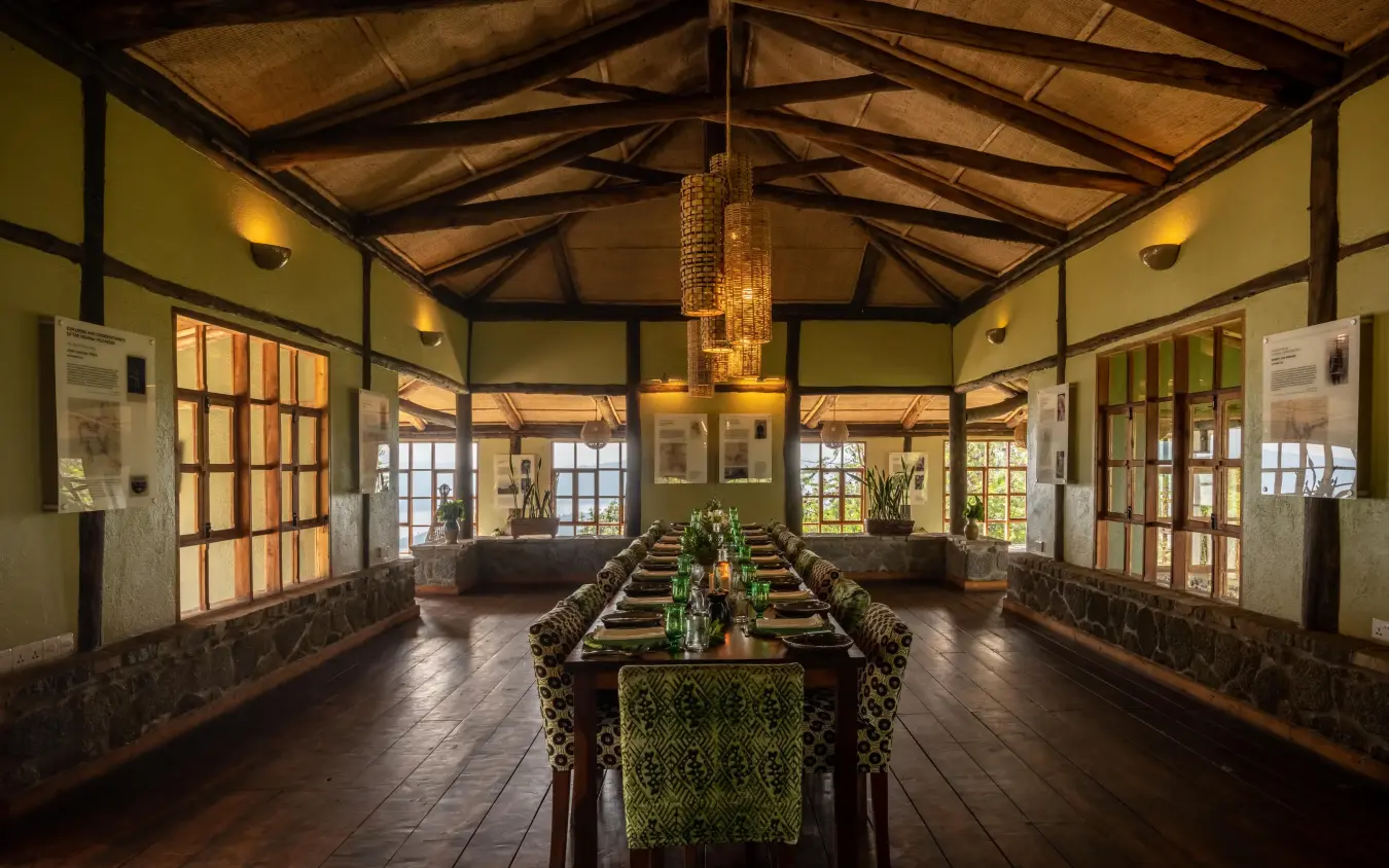 Long dining table set for service in timber lodge hall, Virunga Lodge, Volcanoes National Park, Rwanda