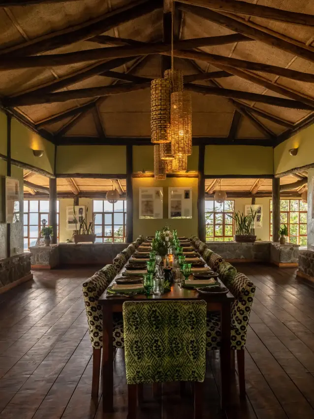 Long dining table set for service in timber lodge hall, Virunga Lodge, Volcanoes National Park, Rwanda