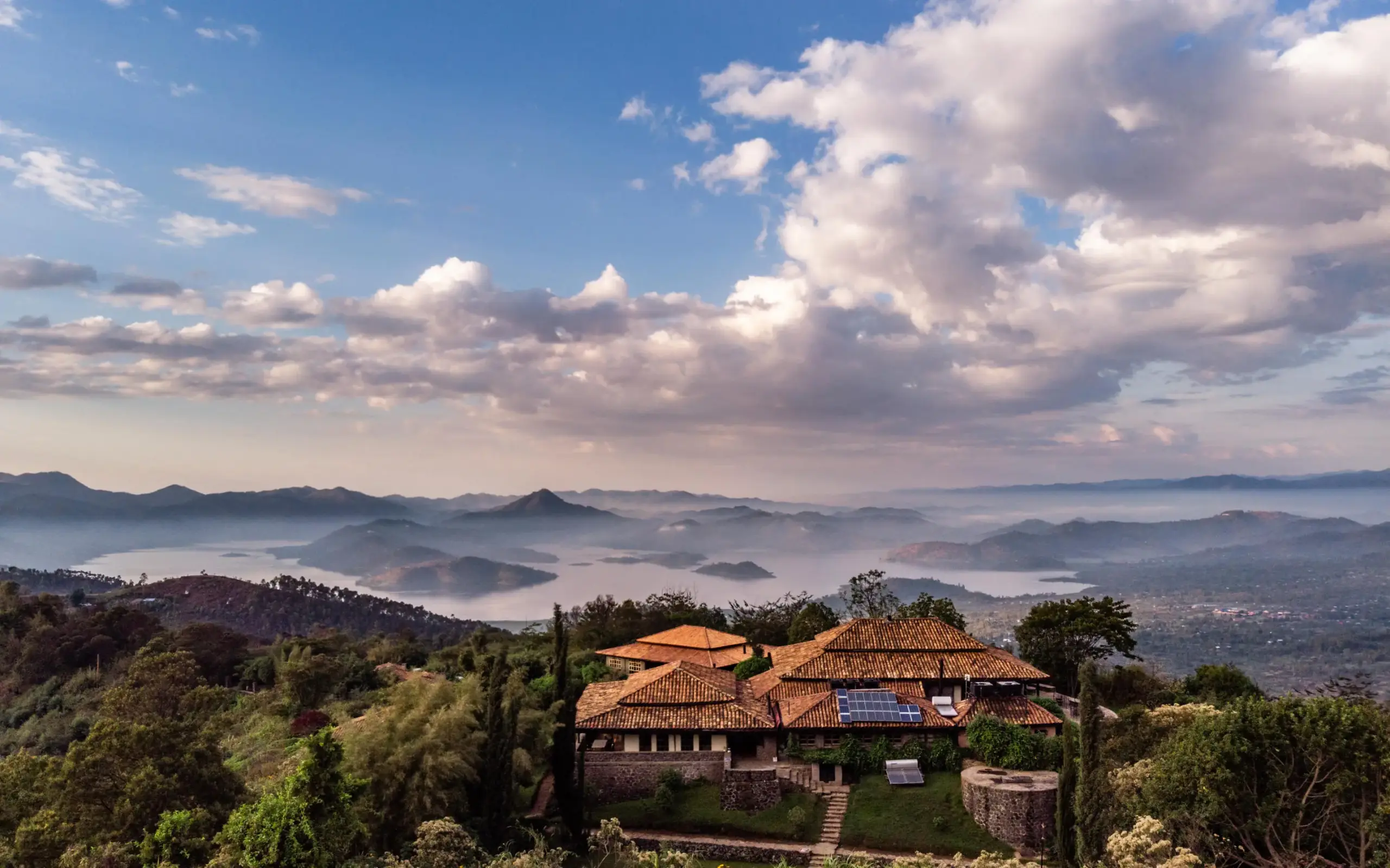 Terracotta-roofed lodge nestled in misty mountain valley, Virunga Lodge, Volcanoes National Park, Rwanda