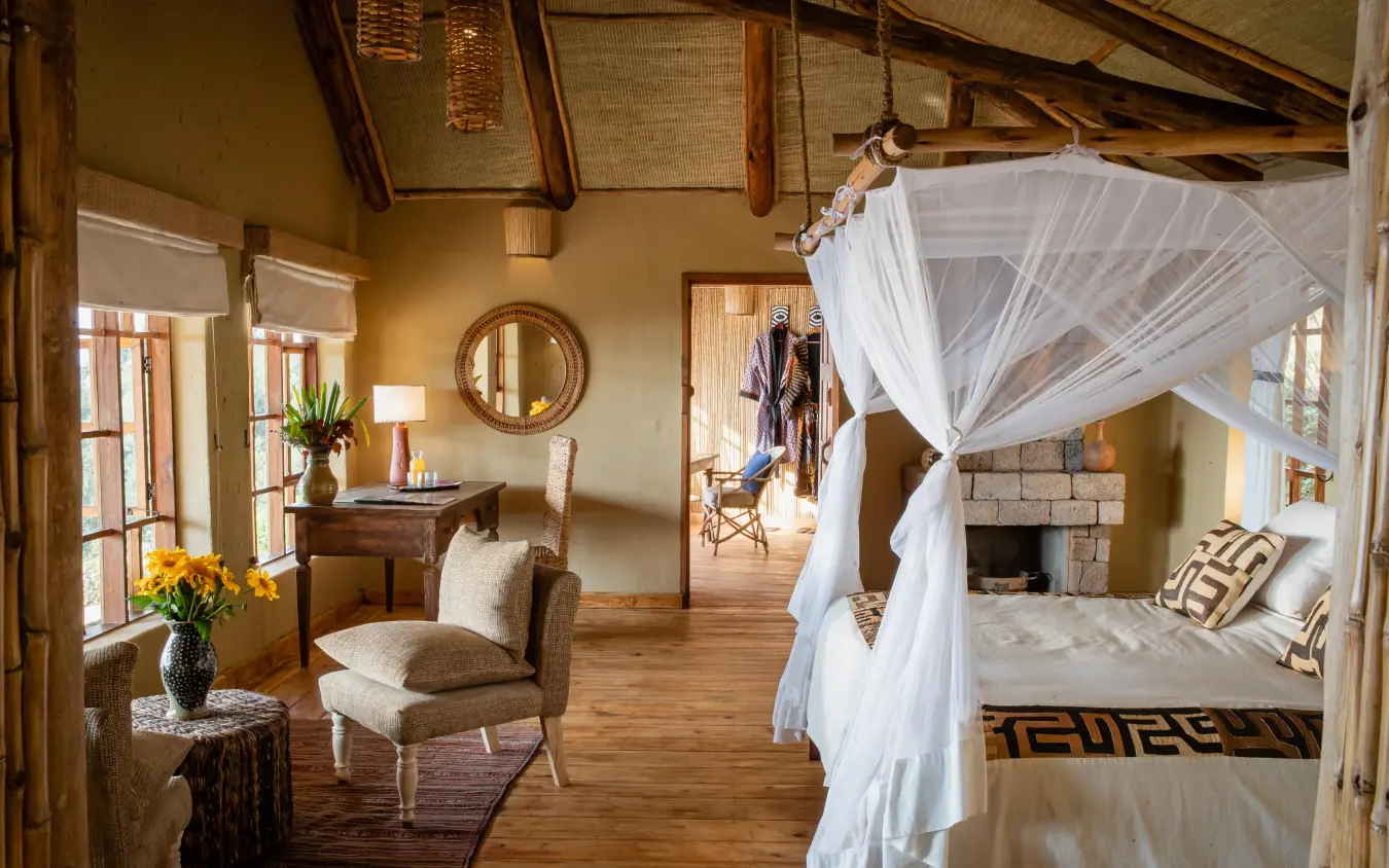 Spacious bedroom with four-poster canopy bed and fireplace, Virunga Lodge, Volcanoes National Park, Rwanda