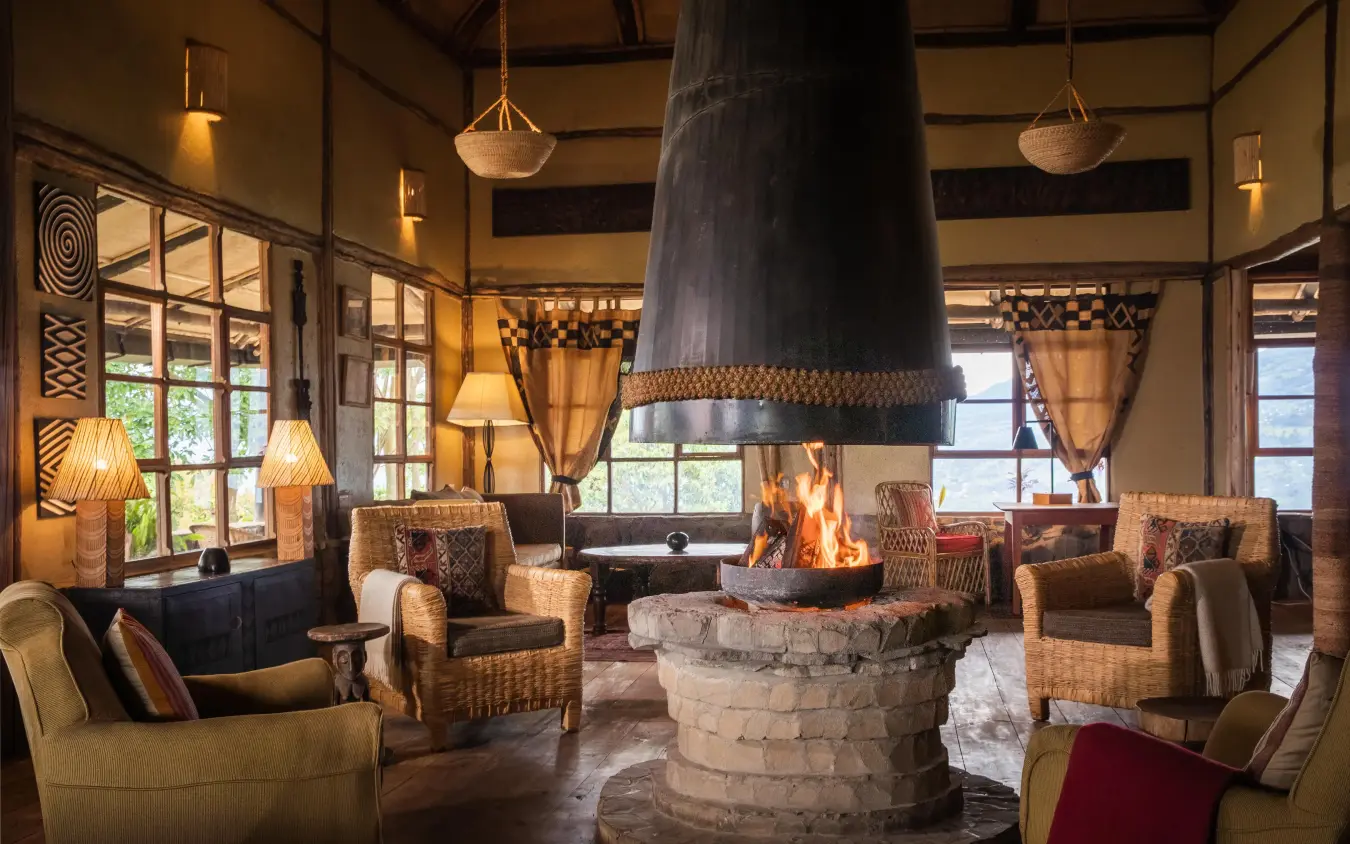 Central fireplace lounge with comfortable seating and large windows, Virunga Lodge, Volcanoes National Park, Rwanda