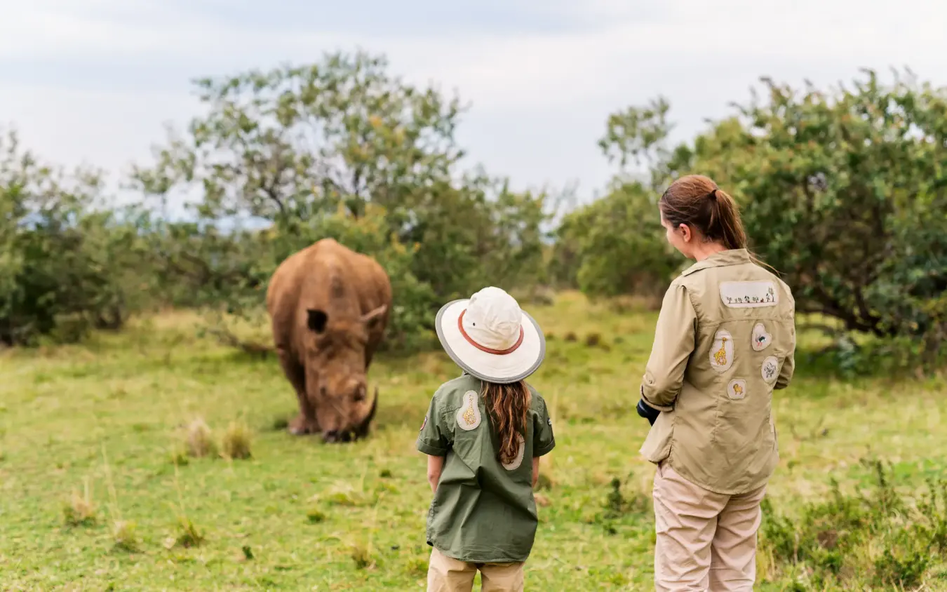 Two children in safari gear observing a rhinoceros