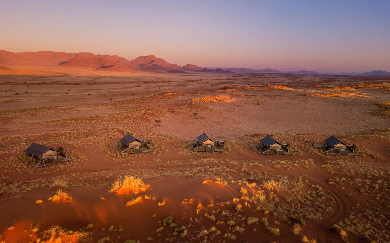 Desert camp tents arranged in landscape at sunset, Wolwedans Dune Camp, NamibRand Private Reserve, Namibia