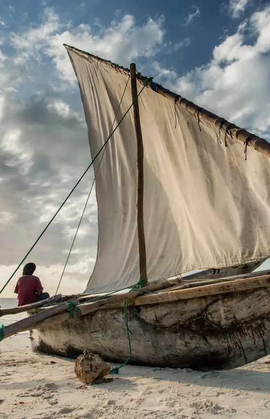 Traditional wooden sailing dhow beached on sandy shore