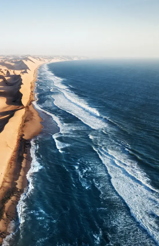 Desert sand dunes meeting ocean waves coastline