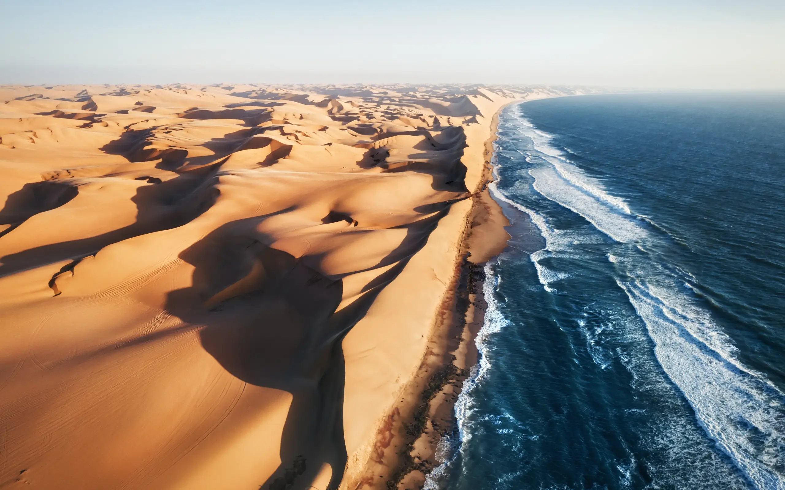 Desert sand dunes meeting ocean waves coastline
