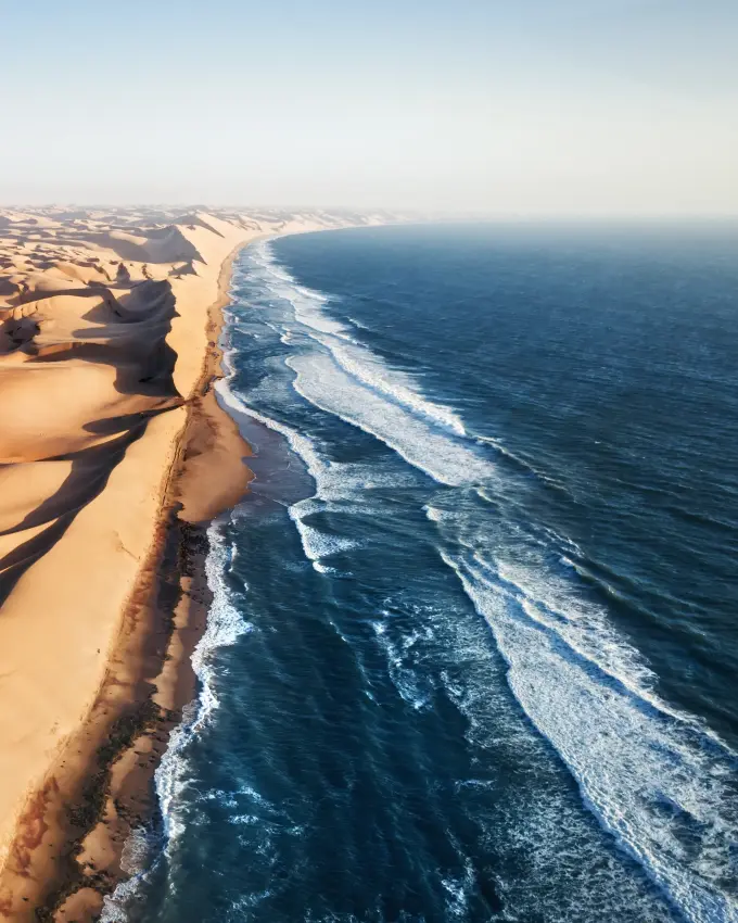 Desert sand dunes meeting ocean waves coastline