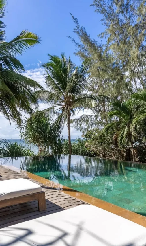 Infinity pool with sun loungers overlooking tropical lagoon and palm trees, Alfajiri Beach Villa, Diani Beach, Kenya