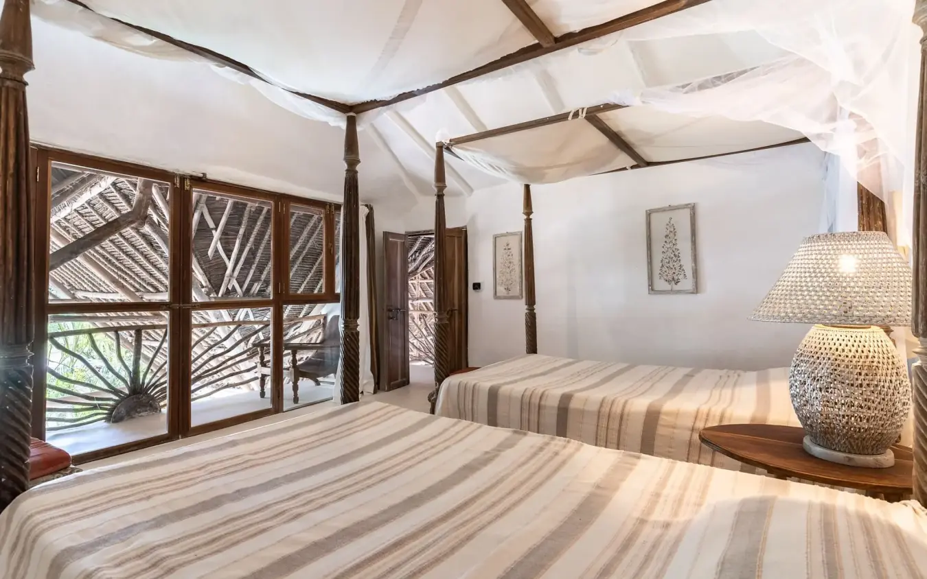 Luxury bedroom with canopy beds and decorative wooden screens overlooking landscape, Alfajiri Beach Villa, Diani Beach, Kenya