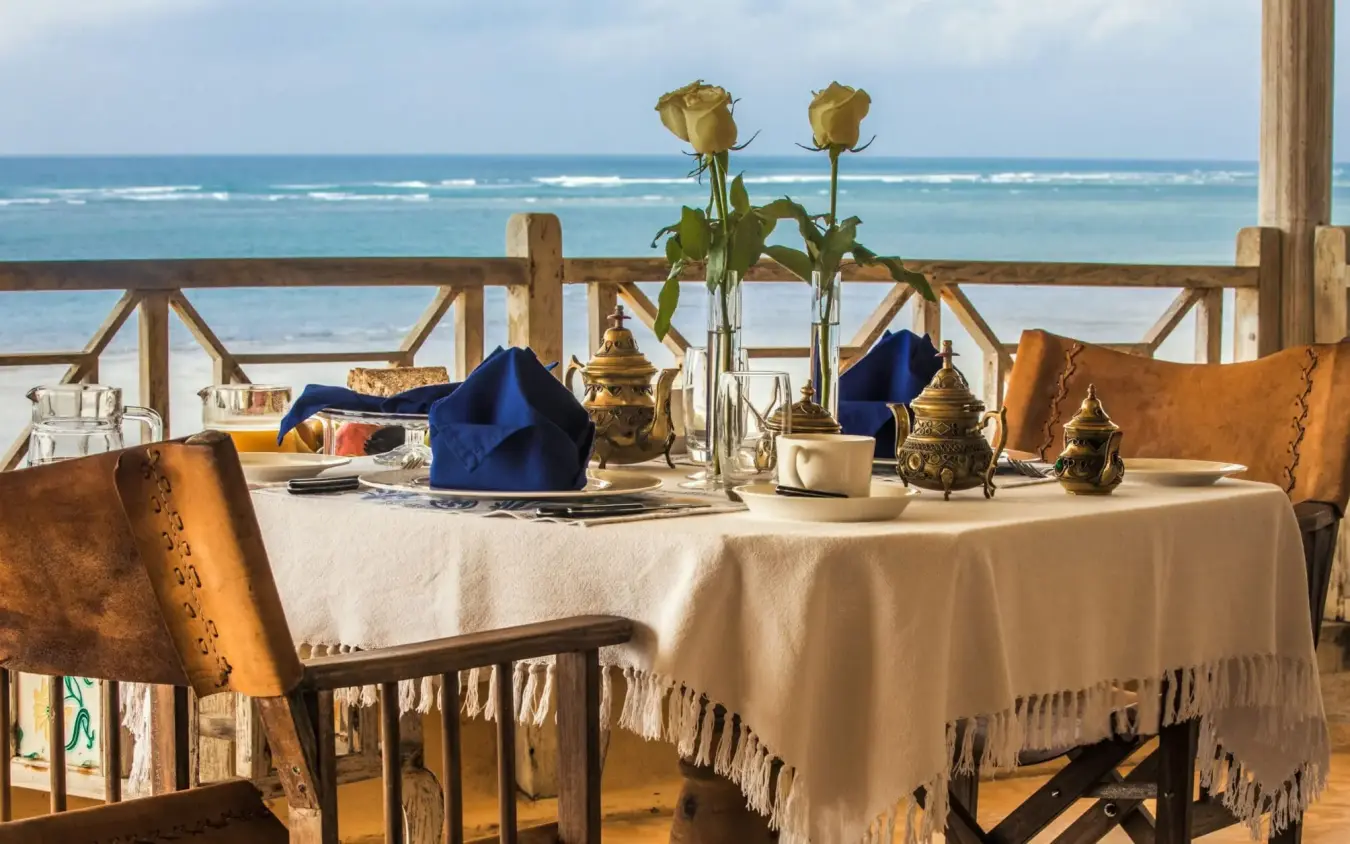 Beachfront dining setup with ocean view and yellow roses, Alfajiri Cliff Villa, Diani Beach, Kenya