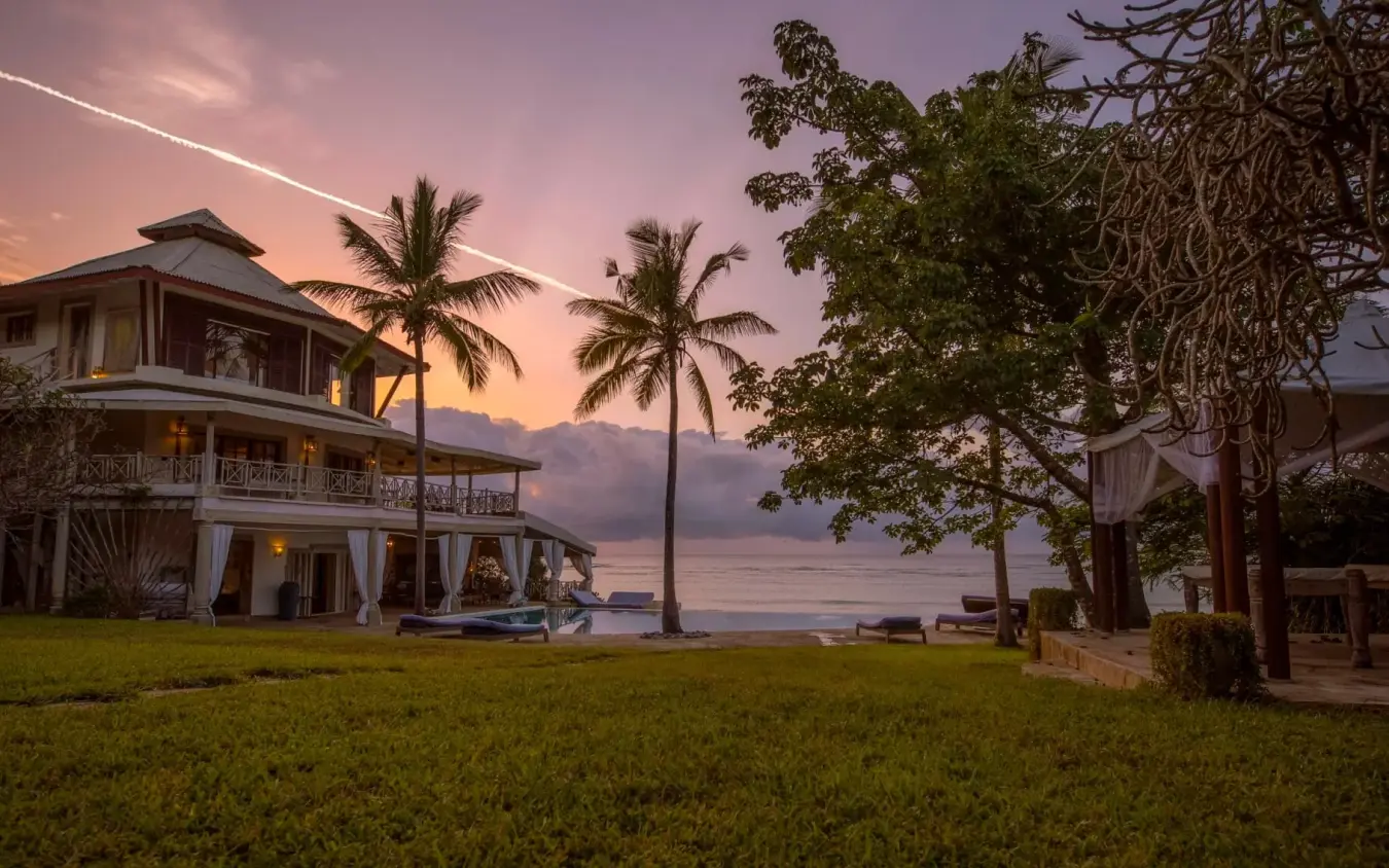 Waterfront villa with palm trees at sunset overlooking calm bay waters, Alfajiri Cliff Villa, Diani Beach, Kenya