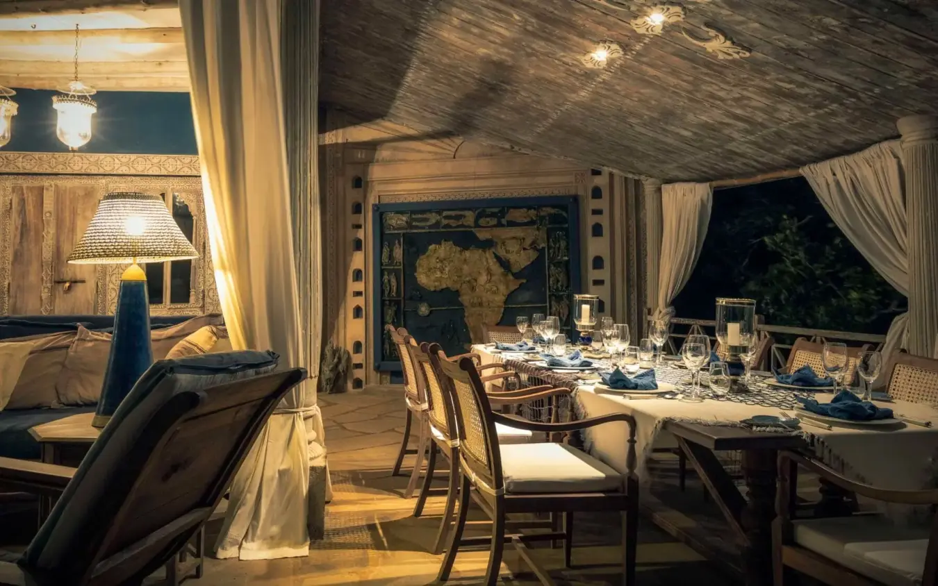 Outdoor dining pavilion set for dinner service at night with draped curtains, Alfajiri Cliff Villa, Diani Beach, Kenya