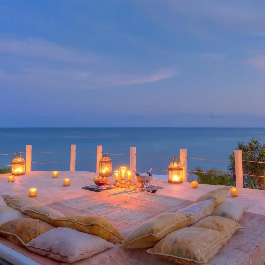 Beachfront terrace with floor cushions and lanterns at dusk overlooking ocean, Diani Beach, Kenya