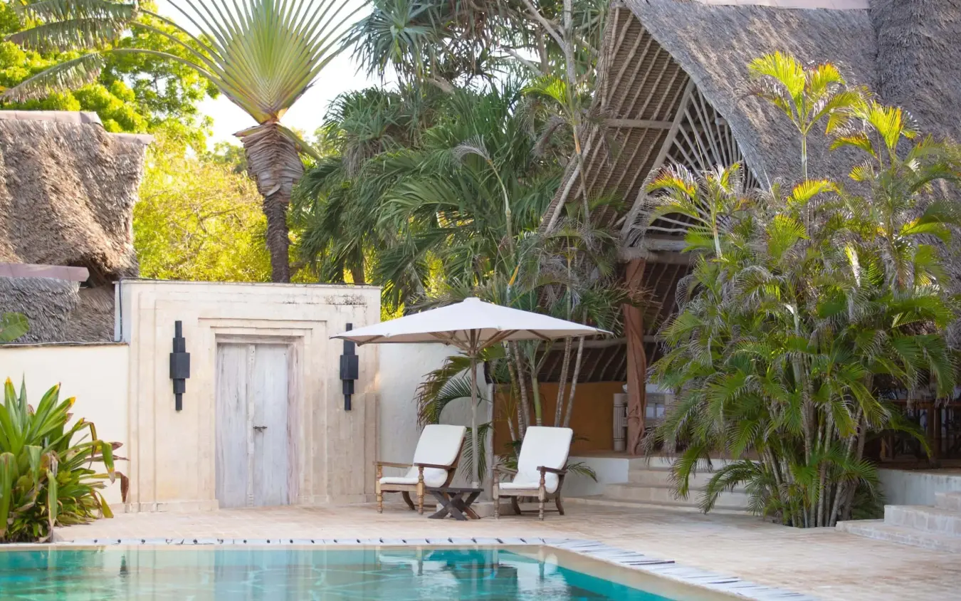 Poolside loungers with umbrella beside whitewashed colonial building, Alfajiri Garden Villa, Diani Beach, Kenya