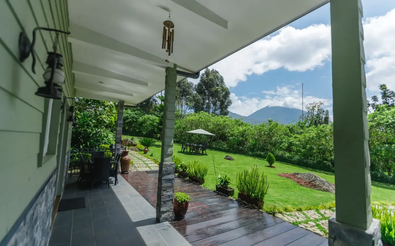 Covered porch overlooking manicured grounds and mountain vista, Amakoro Songa Lodge, Volcanoes National Park, Rwanda