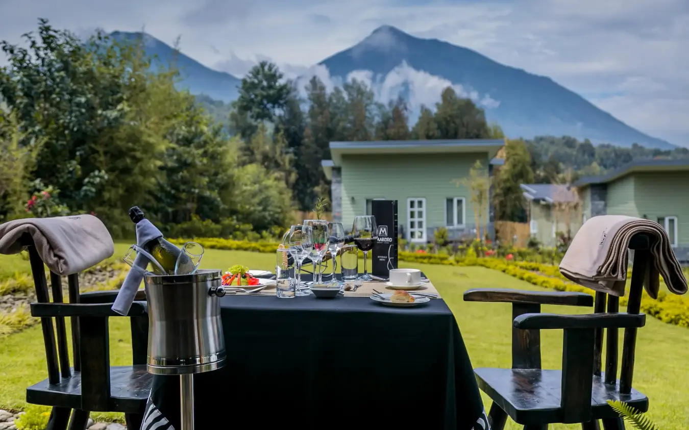 Table setting with mountain views and lodge buildings behind, Amakoro Songa Lodge, Volcanoes National Park, Rwanda