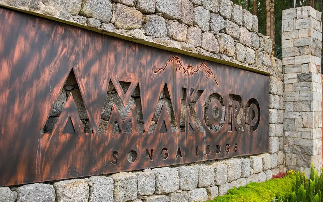 Rustic metal signage mounted on stone wall, Amakoro Songa Lodge, Volcanoes National Park, Rwanda