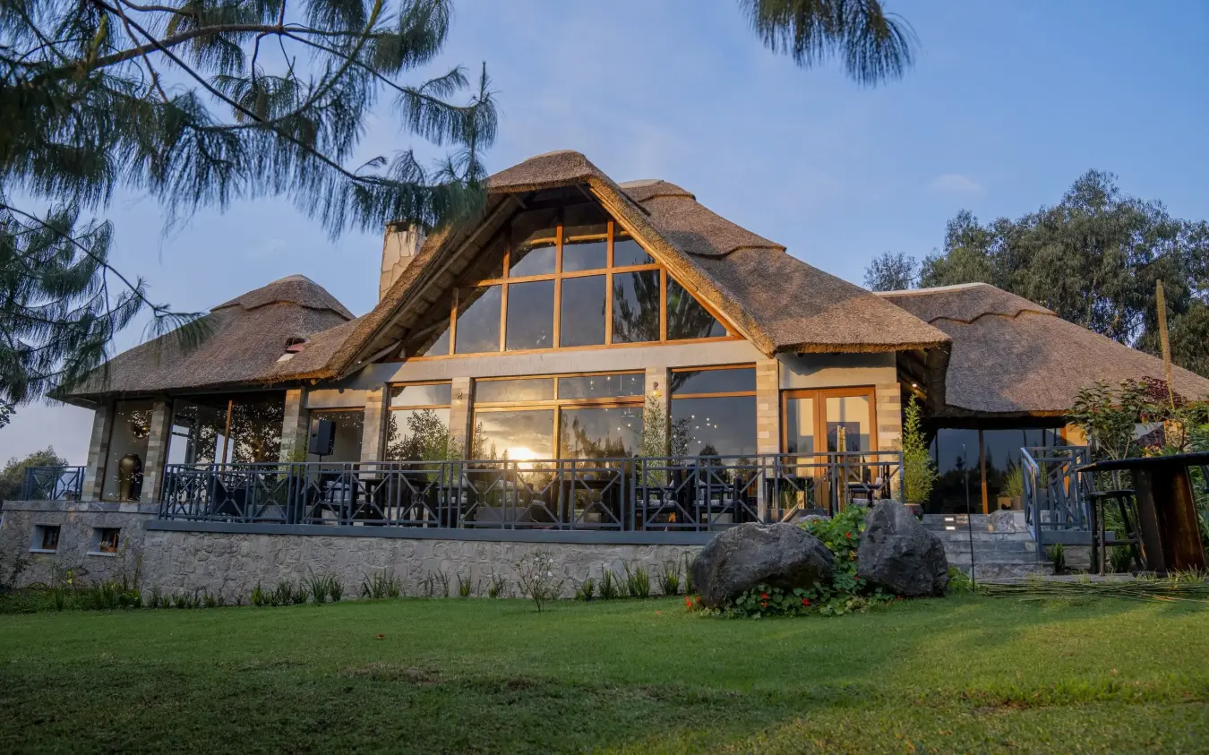 Thatched-roof lodge building with large windows and deck, Amakoro Songa Lodge, Volcanoes National Park, Rwanda