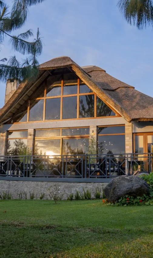 Thatched-roof lodge building with large windows and deck, Amakoro Songa Lodge, Volcanoes National Park, Rwanda