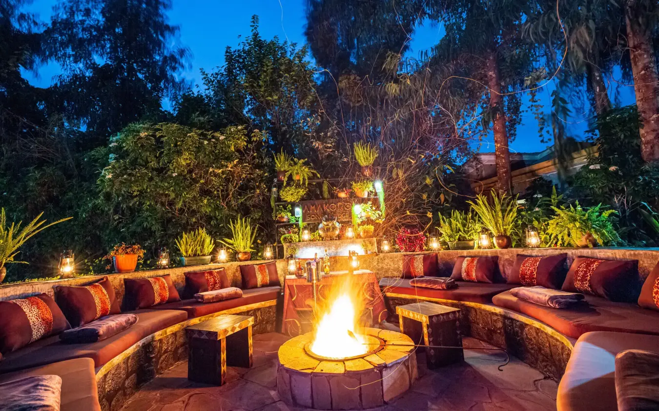 Twilight outdoor lounge area with central fire pit and seating, Amakoro Songa Lodge, Volcanoes National Park, Rwanda
