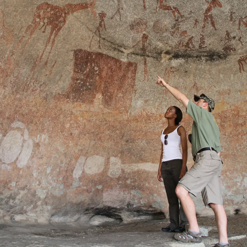 Guests examining ancient rock art on stone wall, Amalinda Lodge, Matobo, Zimbabwe