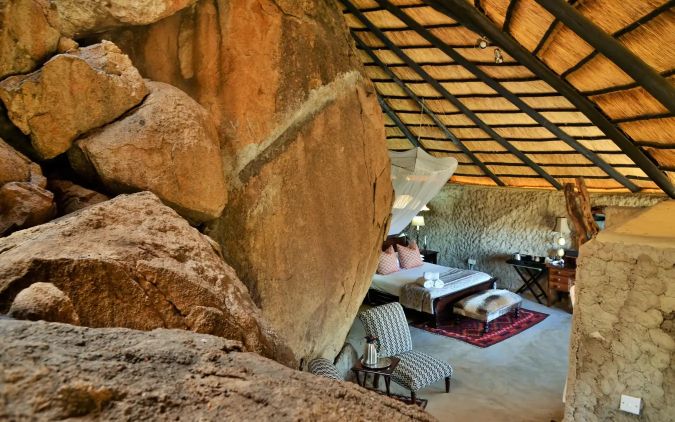 Bedroom interior with large boulder architectural feature overhead, Amalinda Lodge, Matobo, Zimbabwe