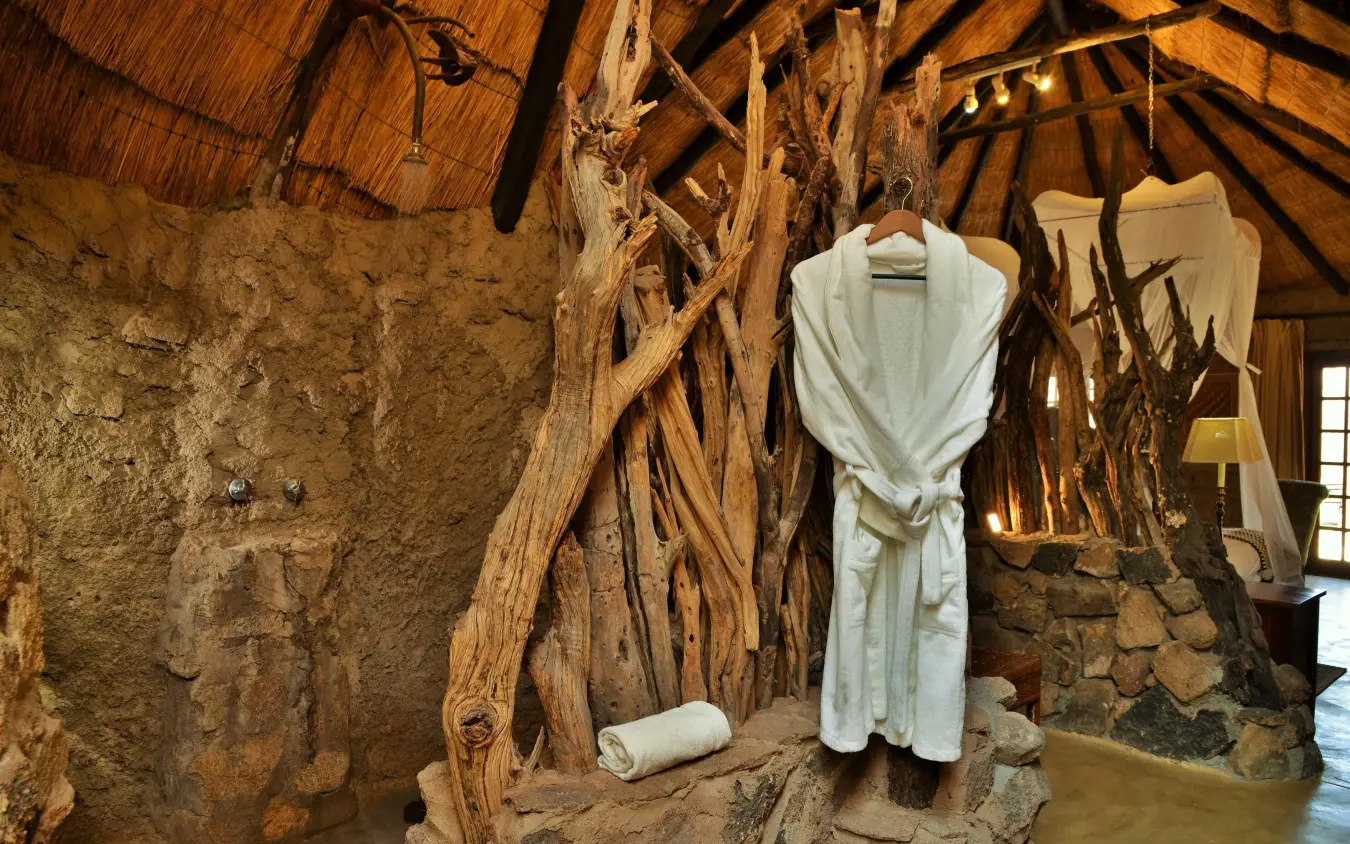 White robe hanging in rustic stone room with wooden beams, Amalinda Lodge, Matobo, Zimbabwe