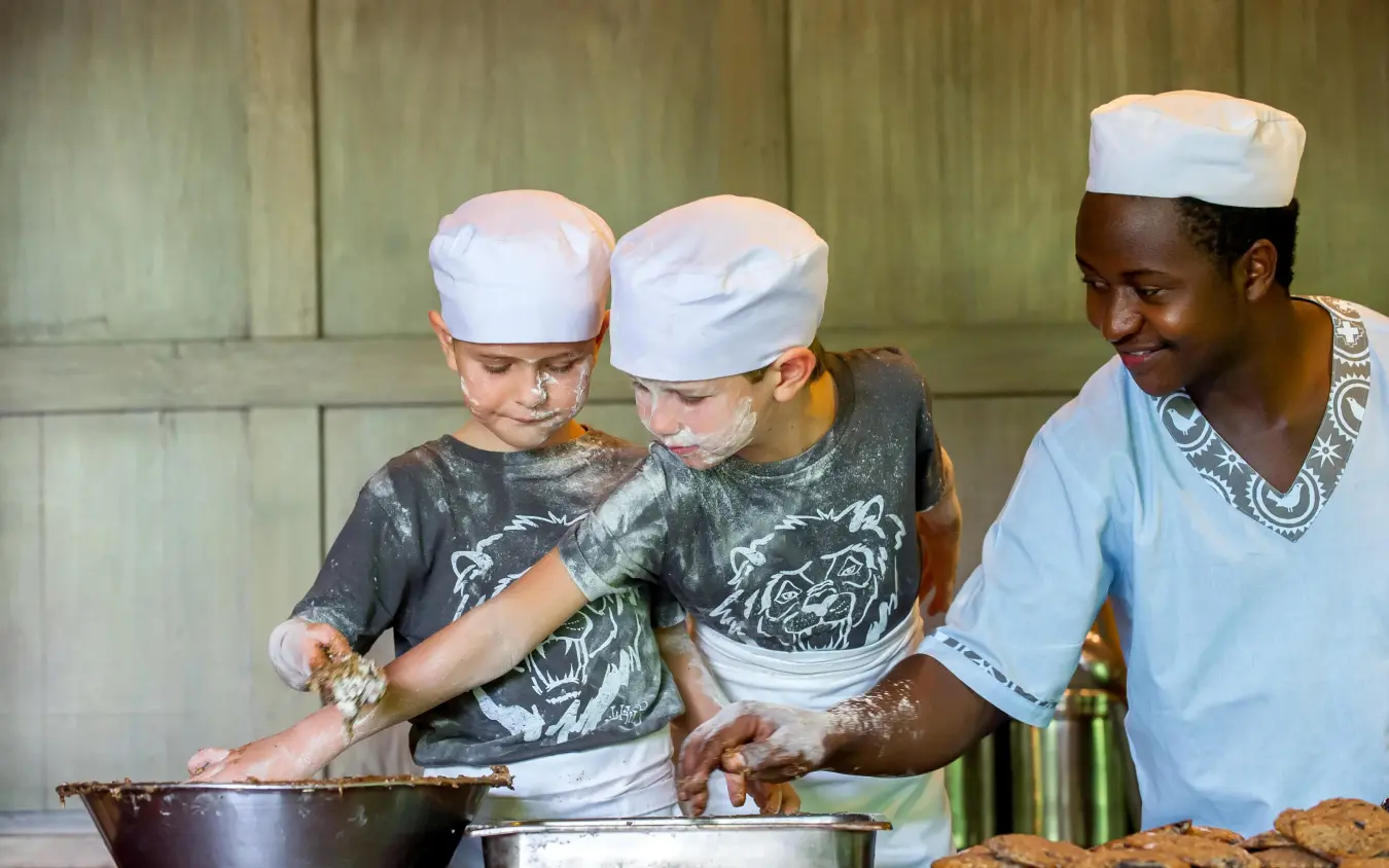Adult and children cooking together in lodge kitchen, Lake Manyara Tree Lodge, Lake Manyara, Tanzania