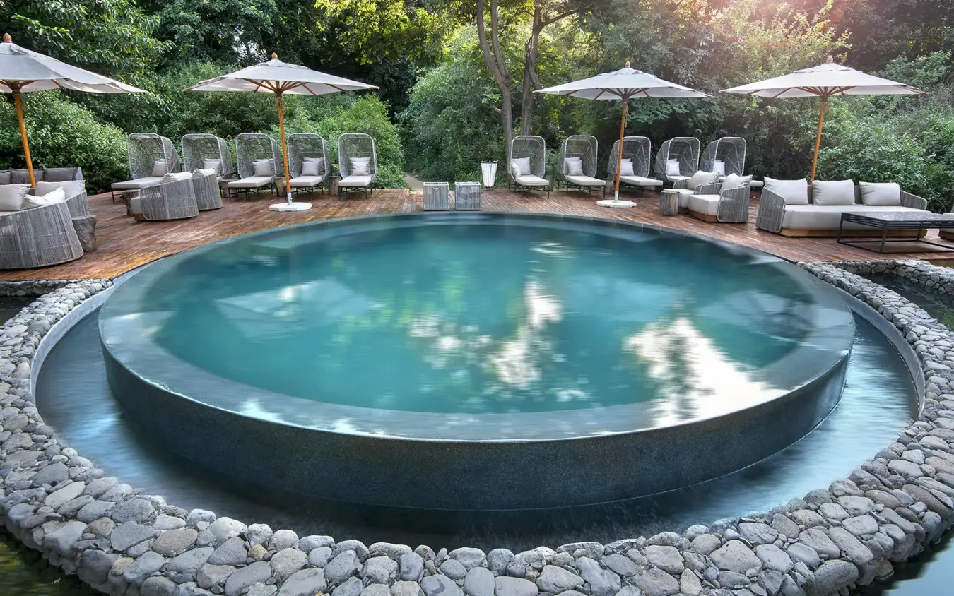 Circular swimming pool surrounded by loungers and umbrellas, Lake Manyara Tree Lodge, Lake Manyara, Tanzania
