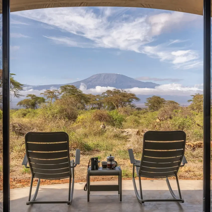 Lounge chairs on viewing deck overlooking acacia woodland with snow-capped volcano, Angama Amboseli, Amboseli and Chyulu Hills, Kenya