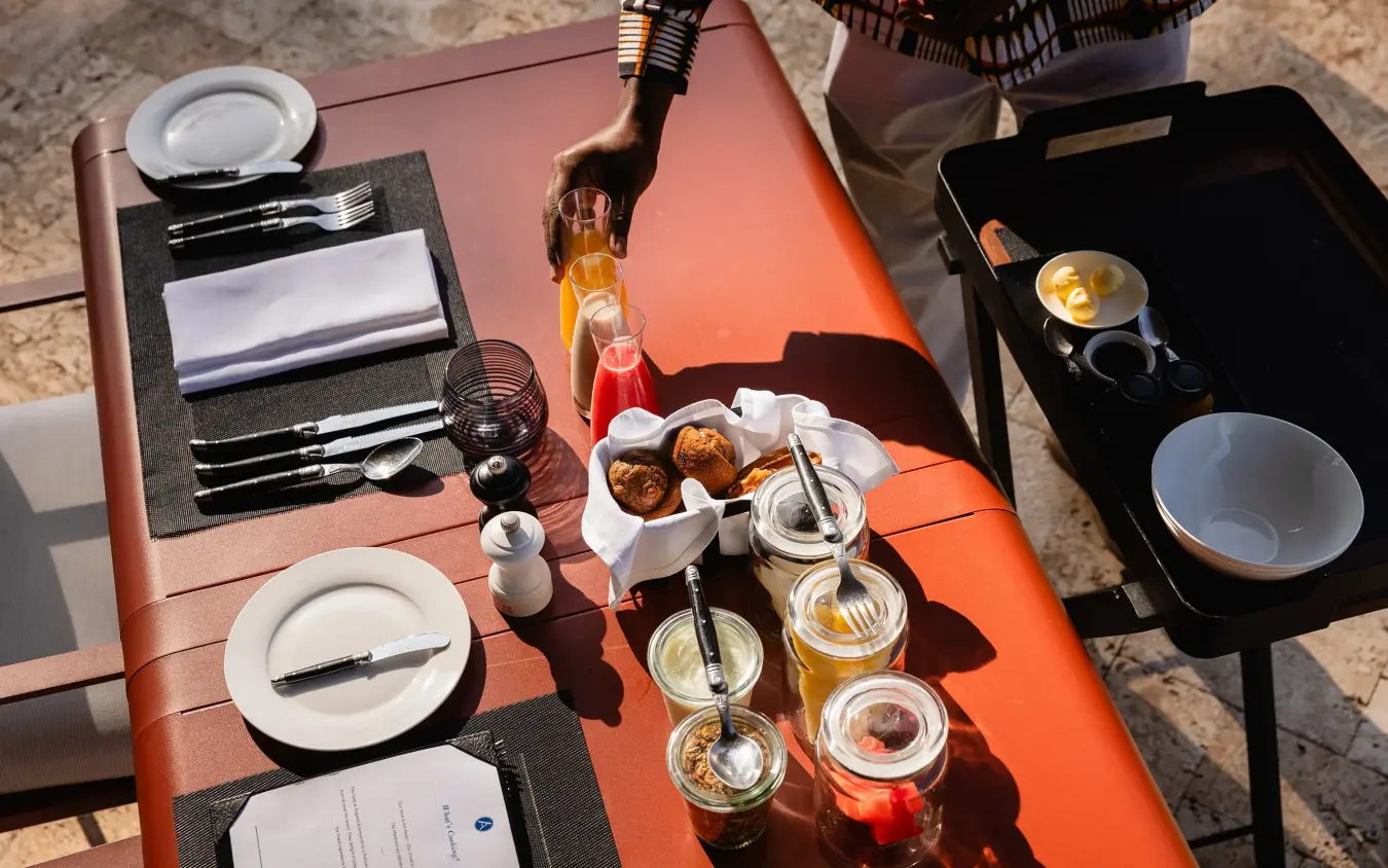 Outdoor dining setup with beverages and plated food on orange table, Angama Amboseli, Amboseli and Chyulu Hills, Kenya