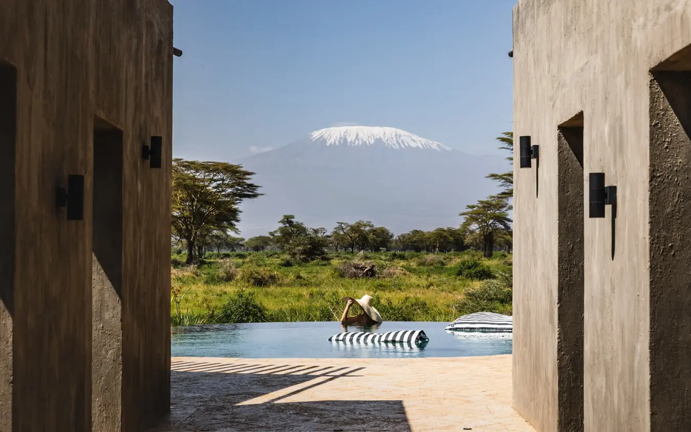 Modern pool and lounge area with snow-capped mountain view beyond savanna, Angama Amboseli, Amboseli and Chyulu Hills, Kenya