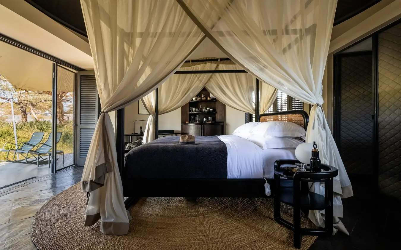 Four-poster canopy bed in luxury safari suite with open veranda view, Angama Amboseli, Amboseli and Chyulu Hills, Kenya