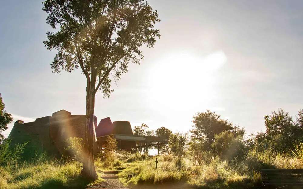 Modern lodge structure elevated above golden grassland, Angama Mara, Maasai Mara, Kenya