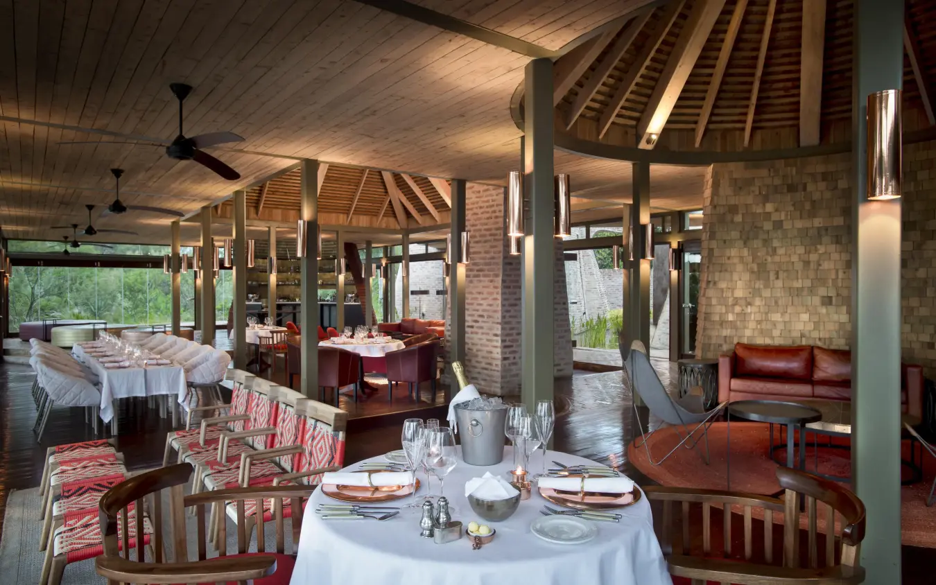 Elegant dining pavilion with set tables and wood beamed ceiling, Angama Mara, Maasai Mara, Kenya