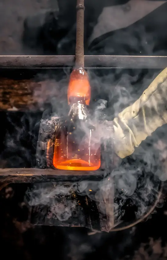 Glassblowing craft with molten glass bottle being shaped over open flame, Arusha Coffee Lodge, Arusha, Tanzania
