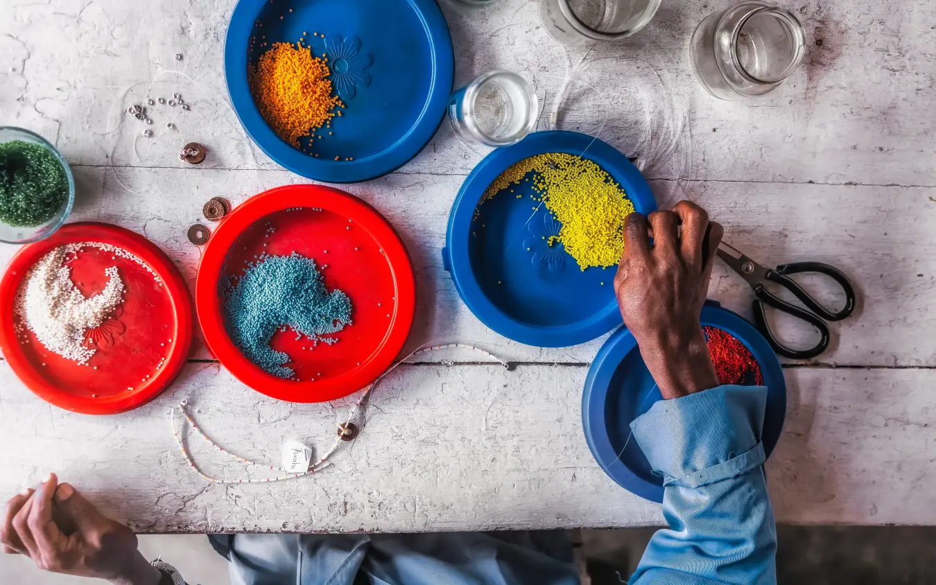 Hands arranging colored powders in bowls on wooden surface, Arusha Coffee Lodge, Arusha, Tanzania