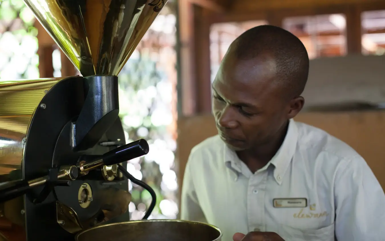 Man operating vintage coffee roaster indoors, Arusha Coffee Lodge, Arusha, Tanzania