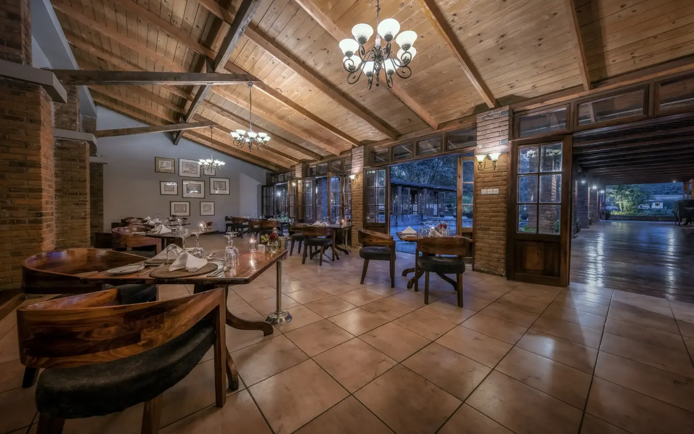 Elegant dining room with exposed wooden beams and evening garden views, Arusha Coffee Lodge, Arusha, Tanzania