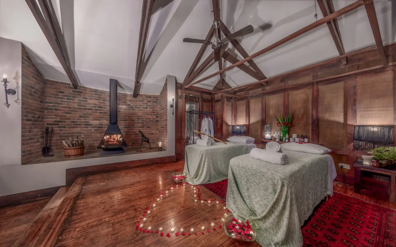 Spa treatment room with twin massage beds and fireplace in converted barn, Arusha Coffee Lodge, Arusha, Tanzania
