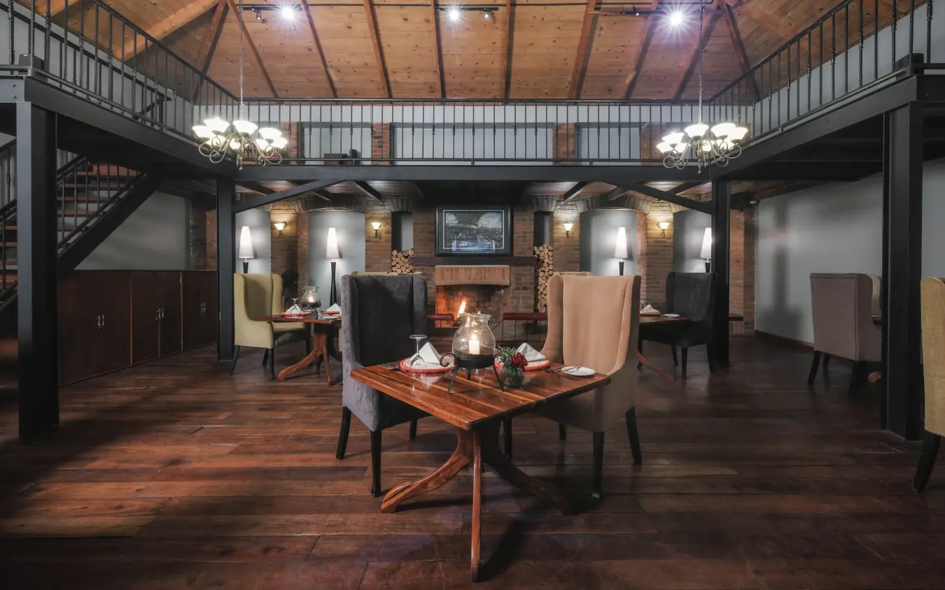Interior lounge with fireplace, wooden beams and safari-style furnishings, Arusha Coffee Lodge, Arusha, Tanzania
