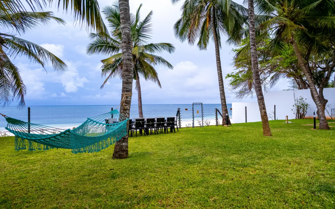 Turquoise hammock strung between palm trees on manicured beachfront lawn, Bahari Bliss, Kilifi, Kenya