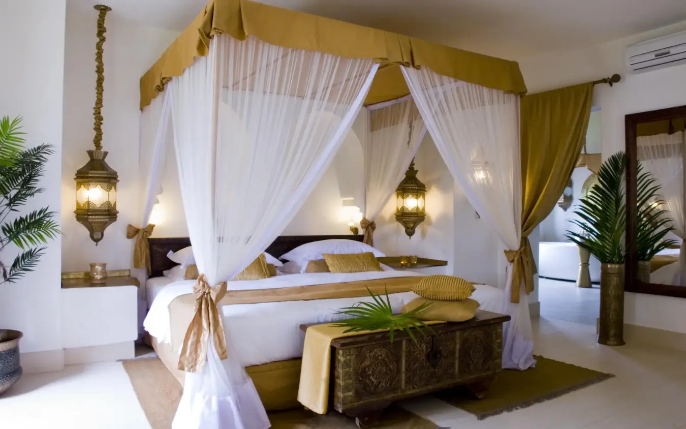 Canopy bed with white drapes and gold accents in luxury bedroom suite, Baraza Resort and Spa, Zanzibar & Pemba, Tanzania
