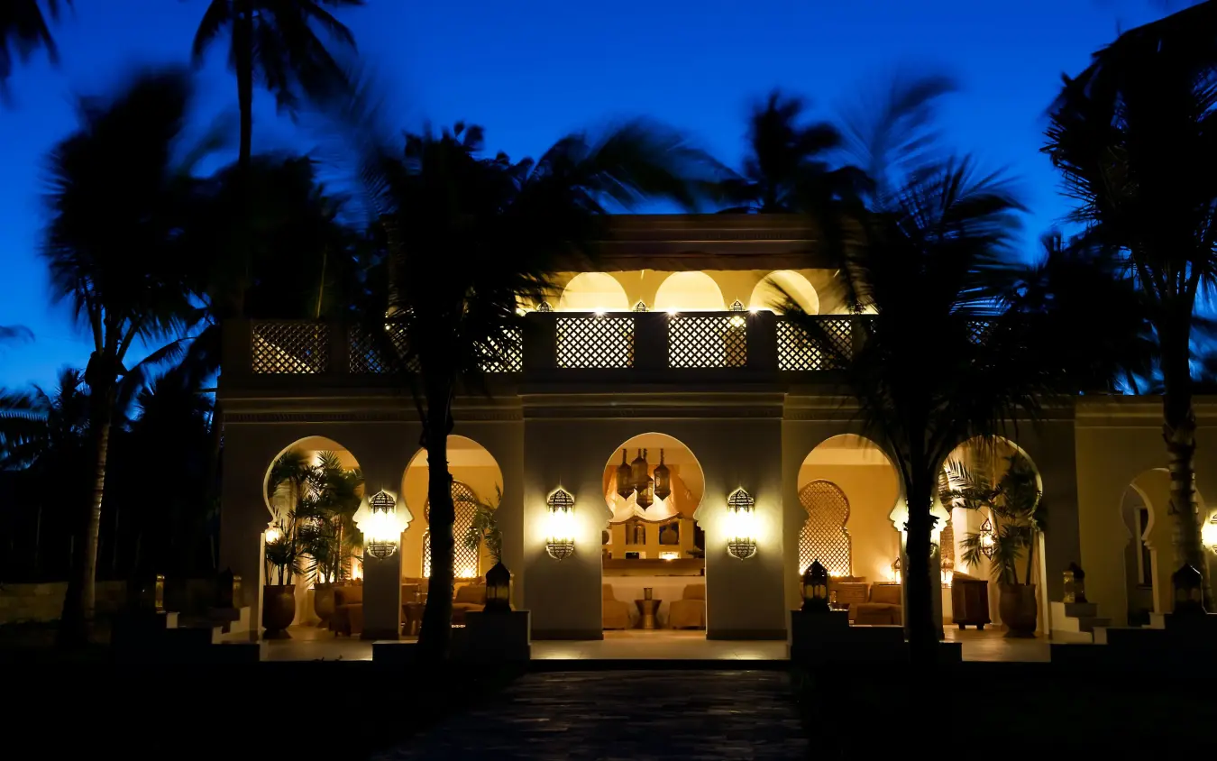 Illuminated coastal lodge building at dusk with palm trees, Baraza Resort and Spa, Zanzibar & Pemba, Tanzania