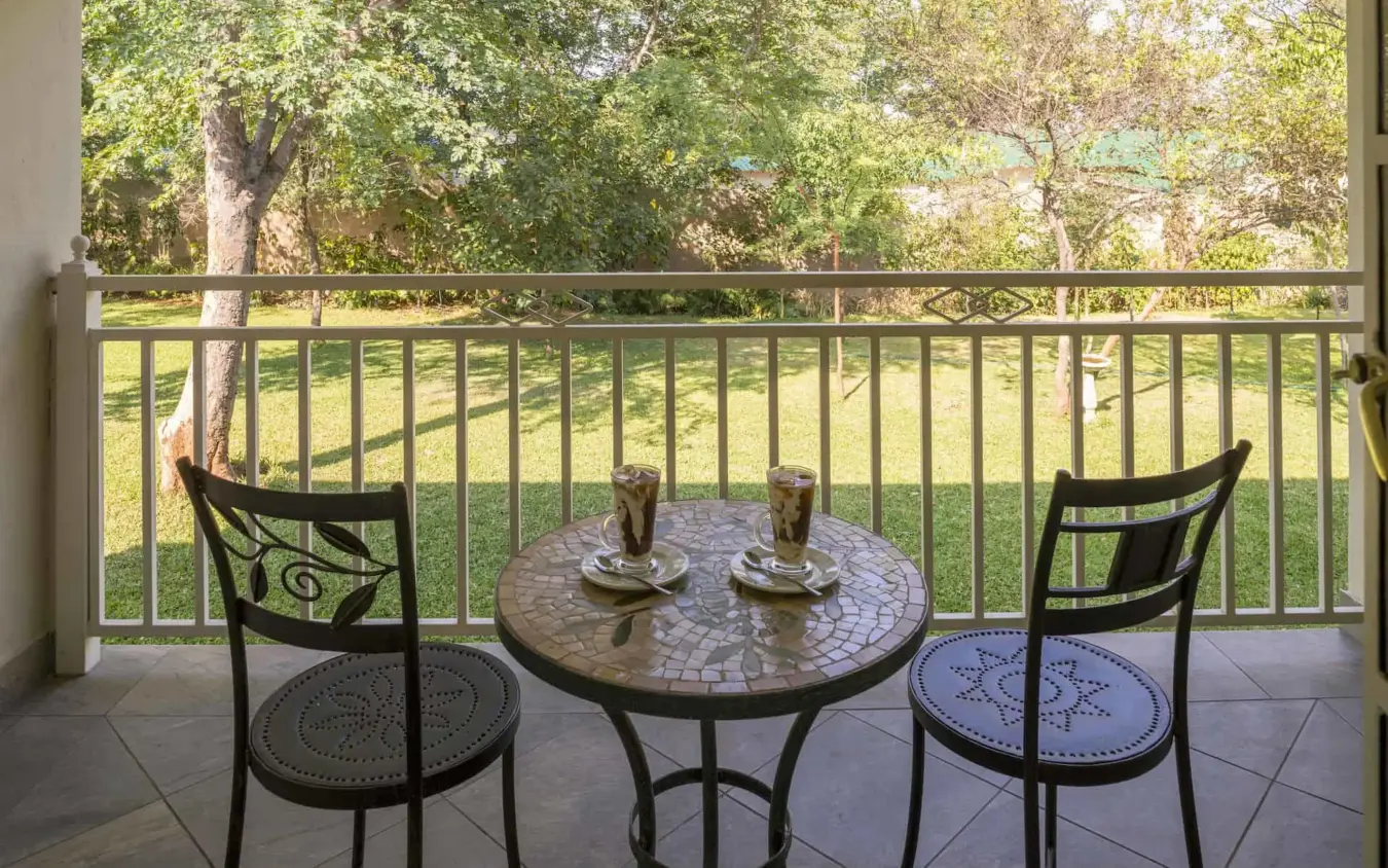 Shaded deck with table chairs overlooking green landscape, Batonka Guest Lodge, Victoria Falls, Zimbabwe