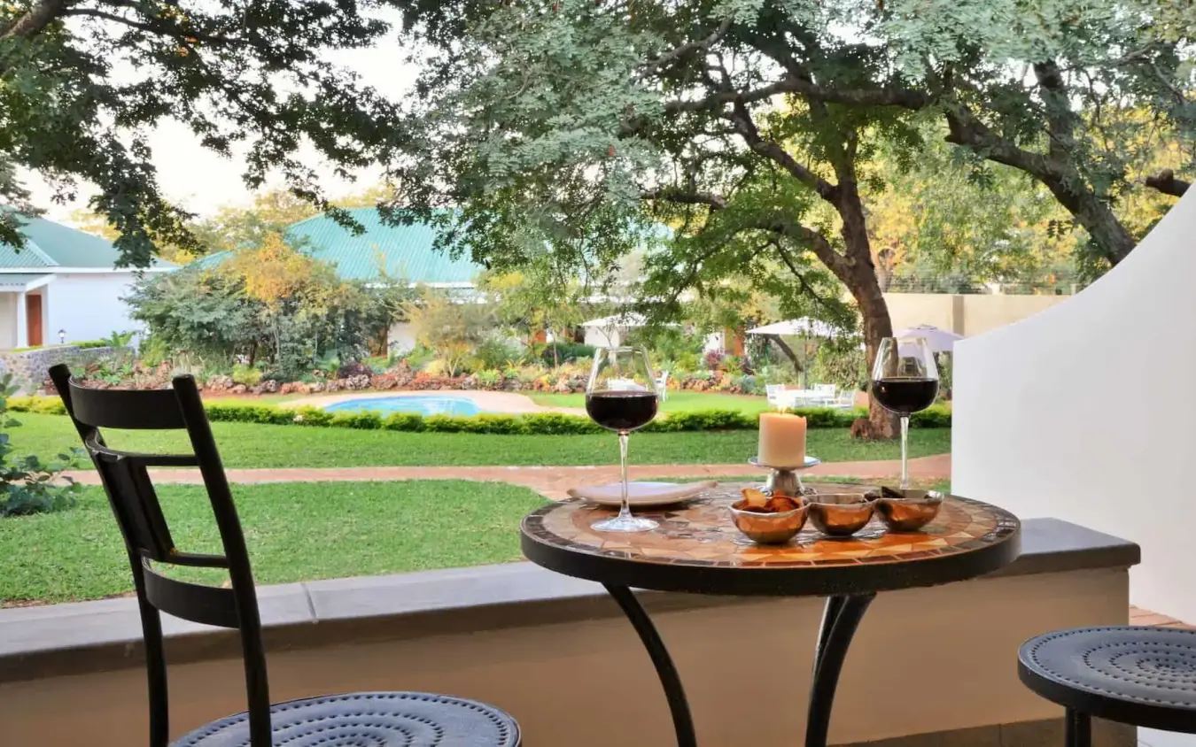 Shaded patio overlooking manicured gardens and lawn, Batonka Guest Lodge, Victoria Falls, Zimbabwe