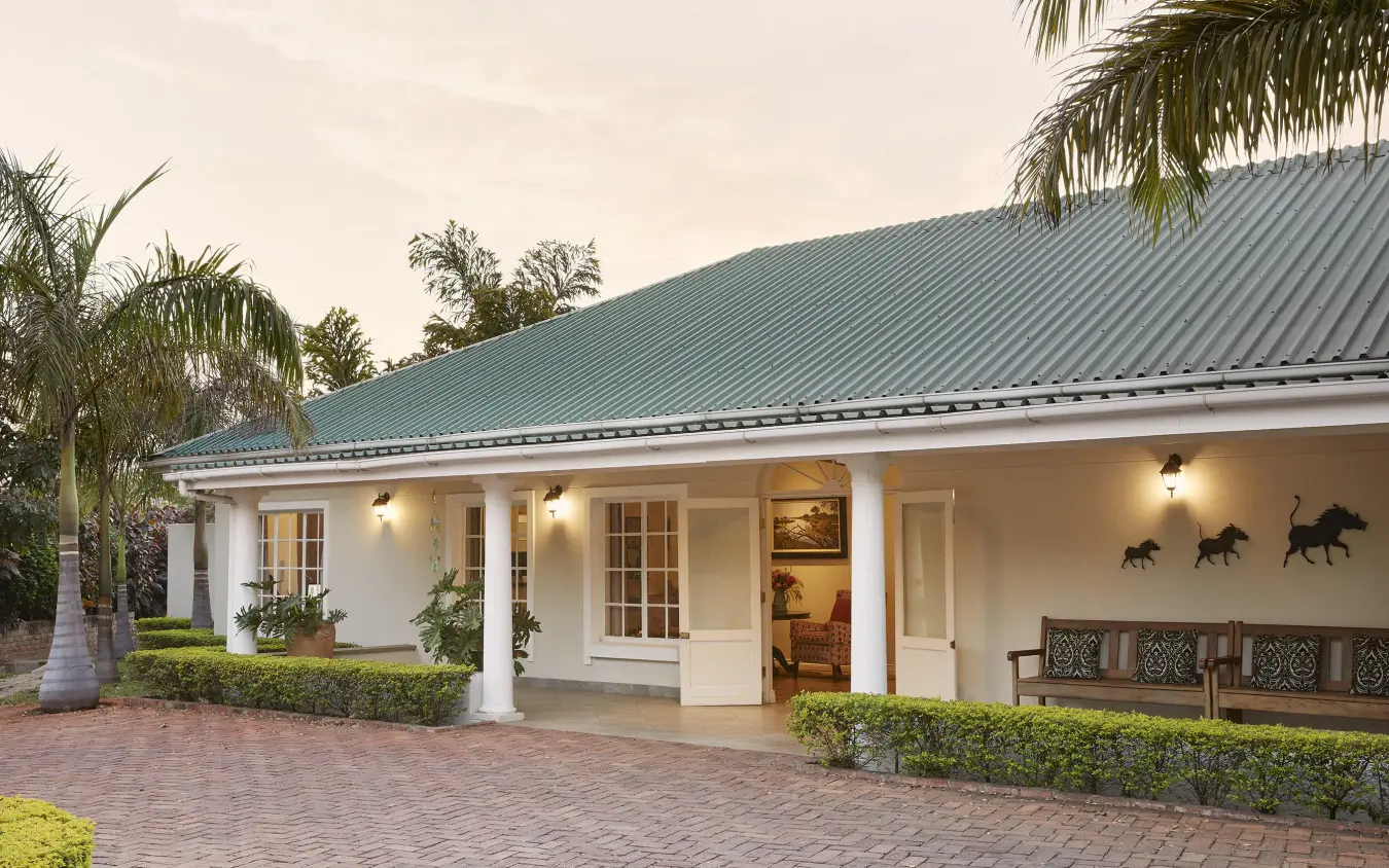 White colonial-style lodge with green metal roof and covered porch, Batonka Guest Lodge, Victoria Falls, Zimbabwe