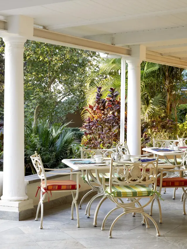 Covered dining terrace with white columns and garden views, Batonka Guest Lodge, Victoria Falls, Zimbabwe