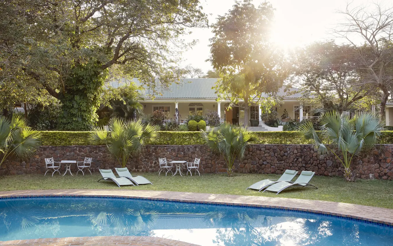 Swimming pool with loungers and main lodge building beyond, Batonka Guest Lodge, Victoria Falls, Zimbabwe